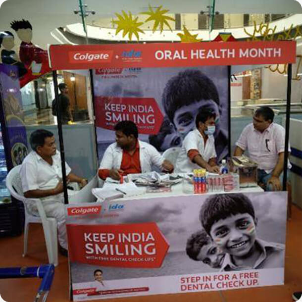 Colgate Oral Health Month free dental check-up booth with dentists consulting patients at a Keep India Smiling campaign setup.