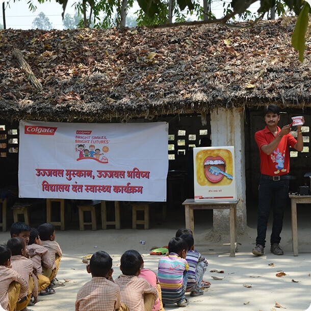 Instructor teaching oral hygiene to school children during a Colgate Bright Smiles, Bright Futures dental health campaign in a village.