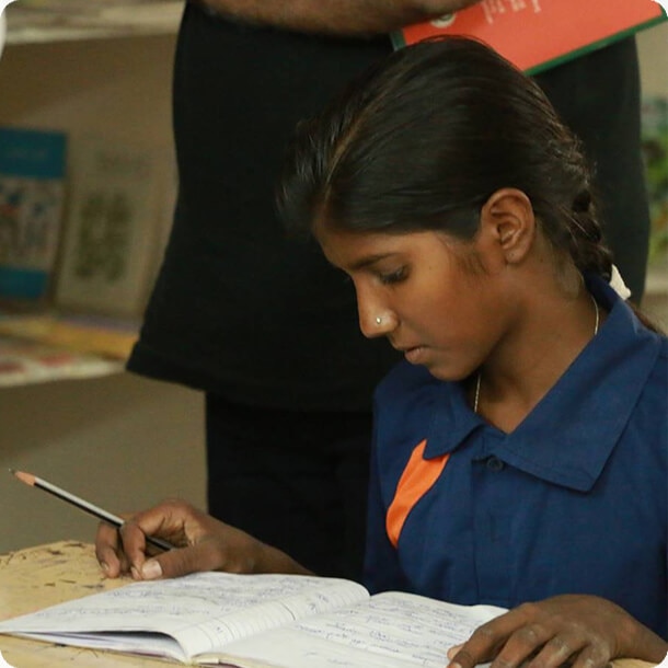 Student focused on writing with a pencil in her notebook during a school class or learning program.